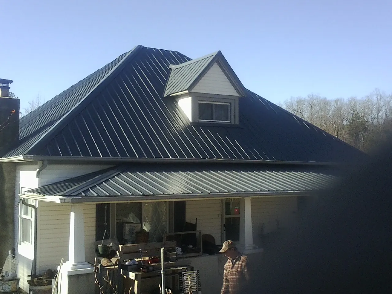 Dark blue standing seam metal roof with a dormer above a front porch in East Berlin