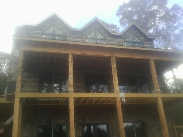 Dormers and porch framing on a large log home under construction — Roof Coating work by our crew in East Berlin