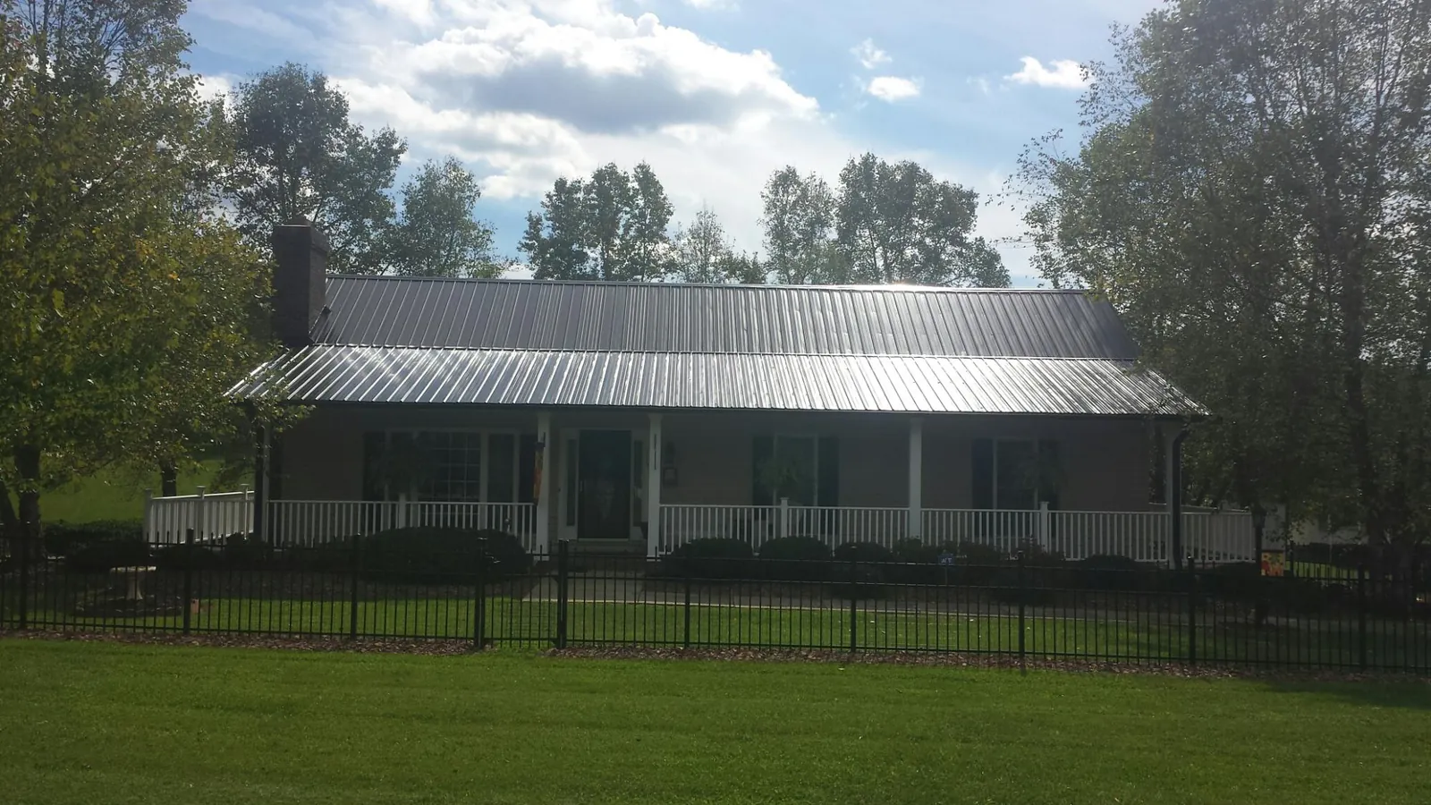Gray metal roof on a brick ranch with a full width front porch — Gutter Guard Installation work by our crew in East Berlin