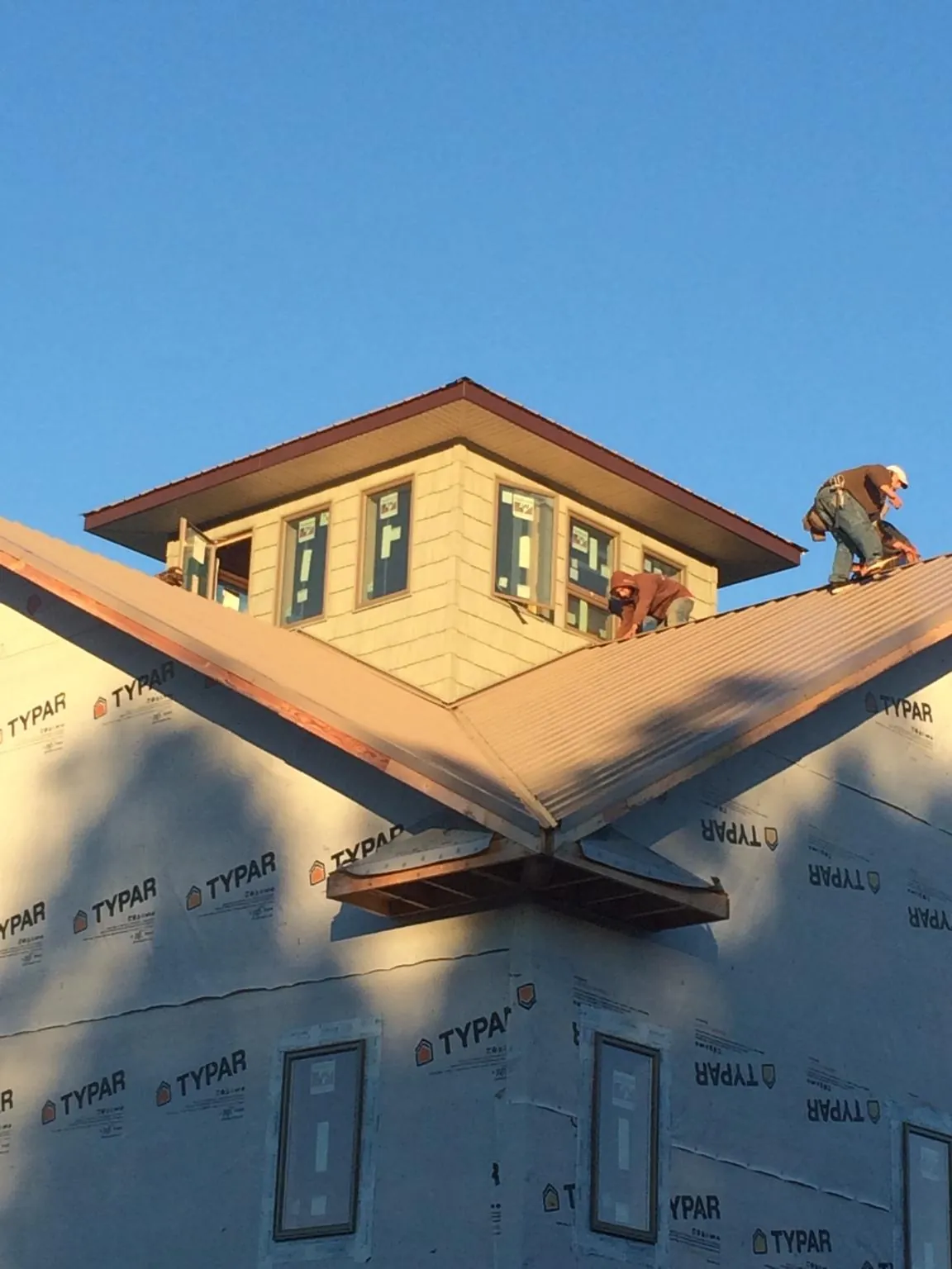 Roofers working around a rooftop cupola on a new metal roof at sunset — Roof Waterproofing in East Berlin by Roofing Brothers